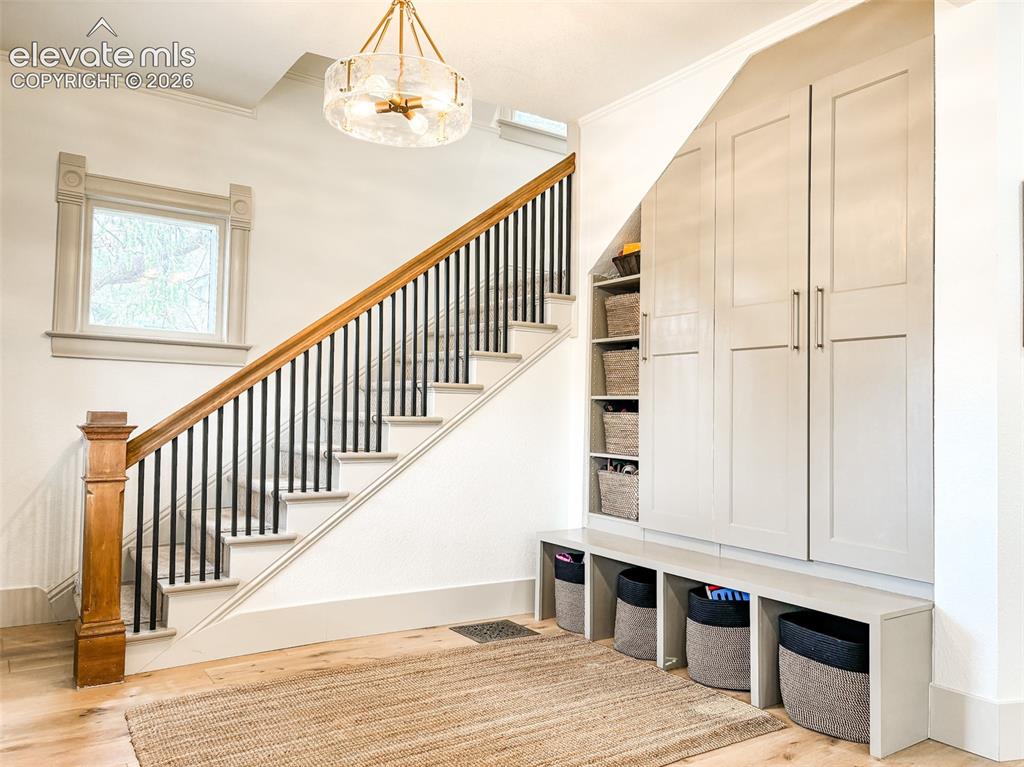 Image 20 of 33: Staircase with wood newel post and handrail, black metal balusters, and whi