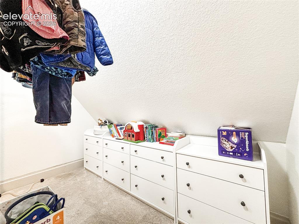 Image 22 of 33: Built-in white storage units with dark hardware, set against a sloped ceili