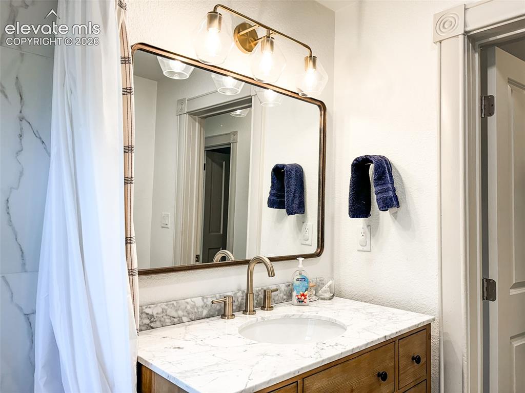 Image 27 of 33: Bathroom vanity featuring a vessel sink, a marble-look countertop, and a wo
