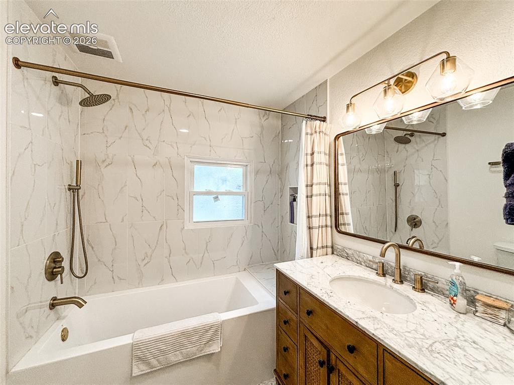 Image 28 of 33: Bathroom featuring a white subway tile surround, a built-in bathtub, a wood