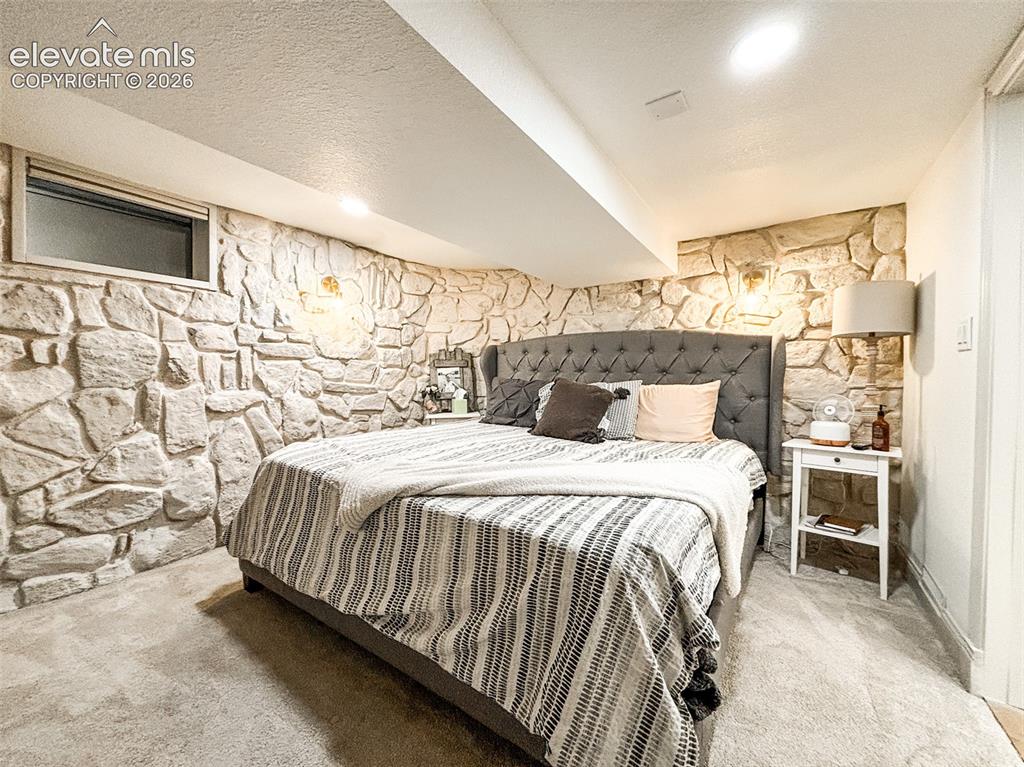 Image 31 of 33: Textured stone accent wall featuring wall sconces in Basement Suite