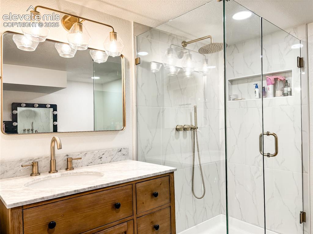 Image 32 of 33: Bathroom featuring a wood-finish vanity with a stone countertop, an undermo