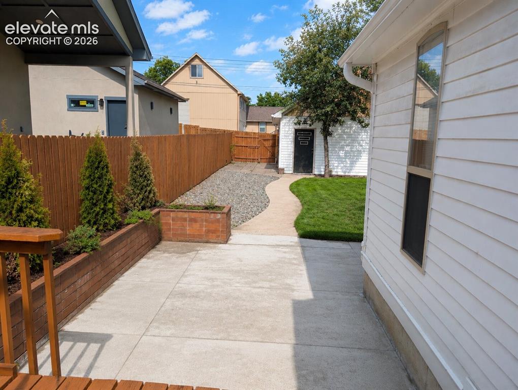 Image 33 of 33: Expansive backyard featuring a manicured lawn, curved concrete pathway, and