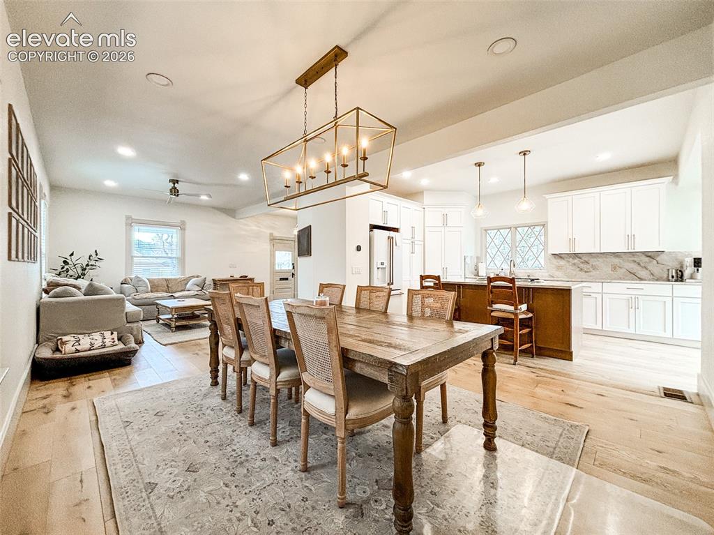 Image 4 of 33: Open-concept living space with light wood-finish flooring, a vaulted ceilin