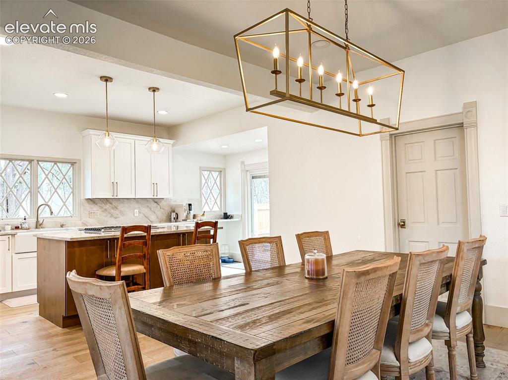 Image 5 of 33: Open-concept space featuring a dining area with a brass chandelier, wood-fi