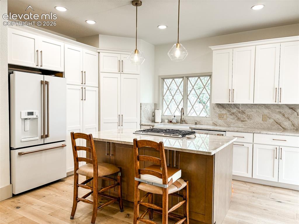 Image 6 of 33: Kitchen featuring white shaker cabinetry, a central island with a lighter w