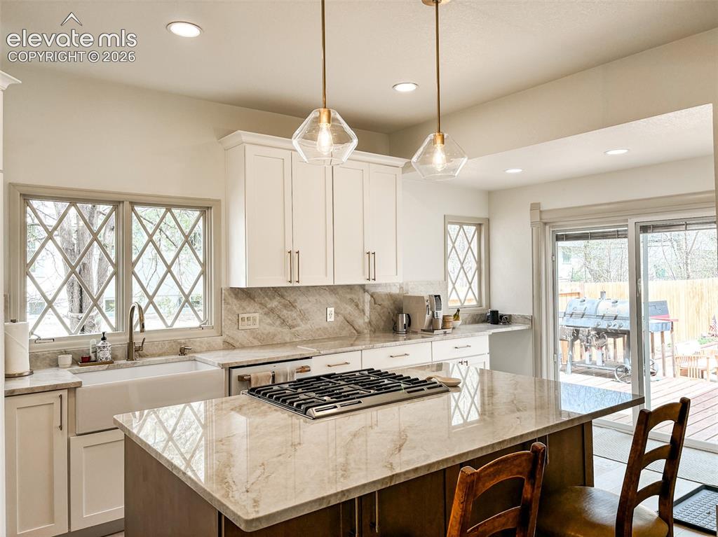 Image 7 of 33: Kitchen featuring white shaker cabinetry, stone countertops, a gas cooktop 