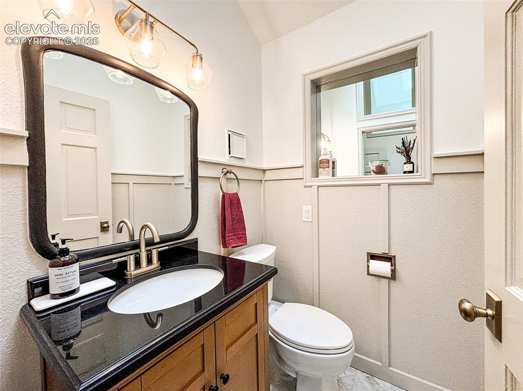 Image 9 of 33: Powder room featuring a single vanity with wood cabinetry and a black count