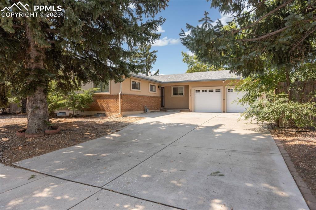Caption: Ranch-style house featuring concrete driveway, a garage, brick siding, and stucco siding