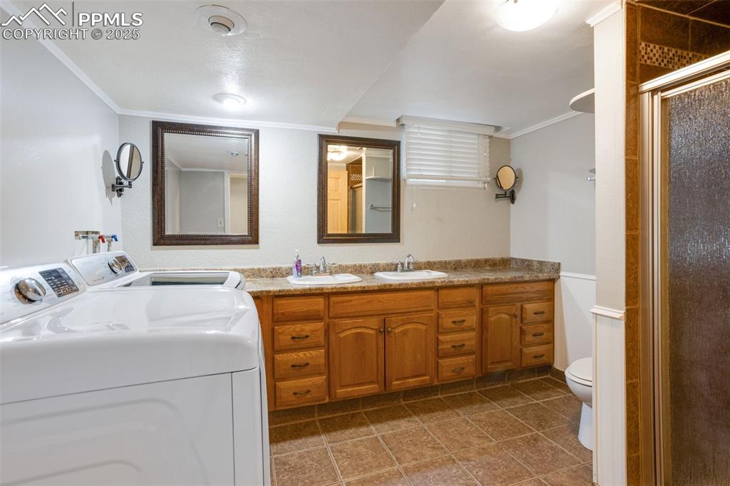 Image 10 of 35: Bathroom featuring ornamental molding, a shower stall, double vanity, washe