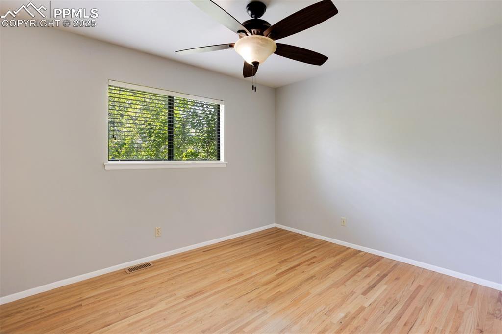 Image 15 of 35: Empty room with light wood finished floors and a ceiling fan