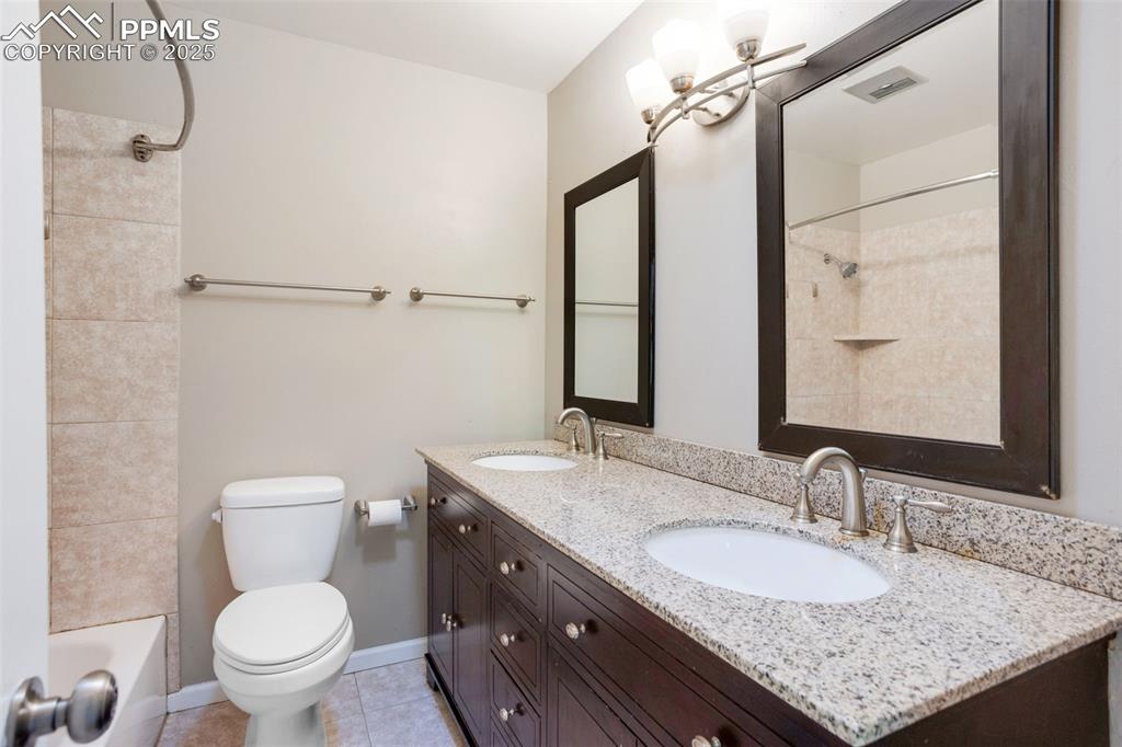 Image 16 of 35: Bathroom with double vanity, shower / bath combination, and light tile patt
