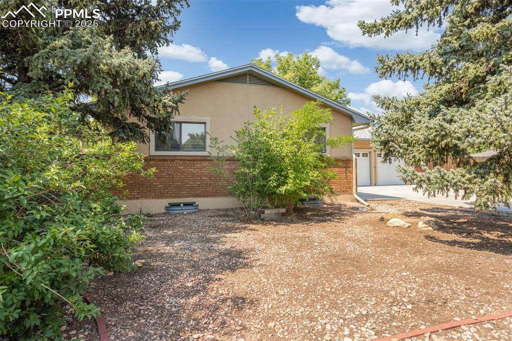Image 2 of 35: View of property exterior with brick siding, a garage, stucco siding, and c