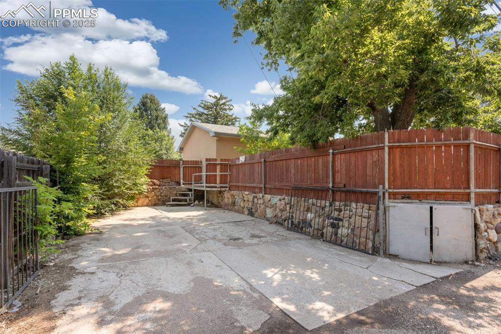 Image 23 of 35: Fenced backyard with a patio