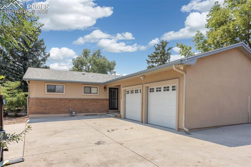Image 3 of 35: Ranch-style house featuring concrete driveway, stucco siding, brick siding,