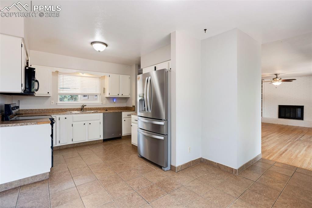 Image 7 of 35: Kitchen with white cabinets, stainless steel appliances, a fireplace, and l