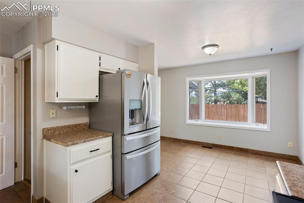 Image 8 of 35: Kitchen featuring stainless steel fridge with ice dispenser, white cabinets