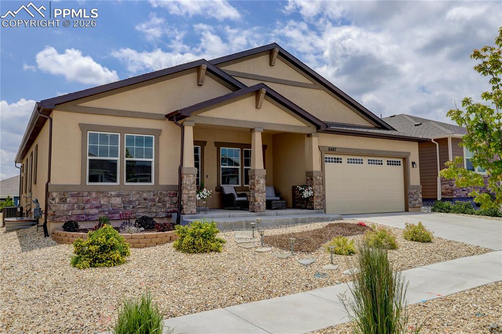 Caption: Craftsman house featuring a porch, stucco siding, driveway, stone siding, and a garage