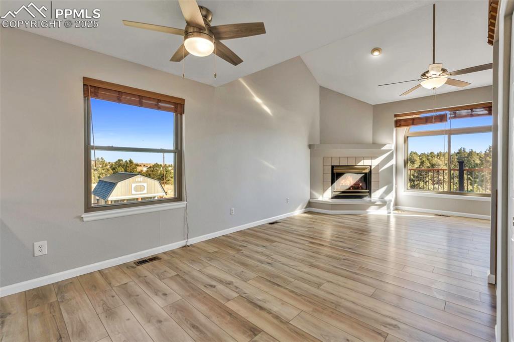 Image 18 of 47: Unfurnished living room featuring a ceiling fan, a fireplace, and light woo