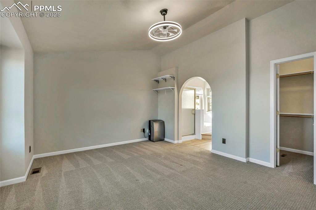Image 28 of 47: Unfurnished bedroom with light colored carpet, arched walkways, a walk in c