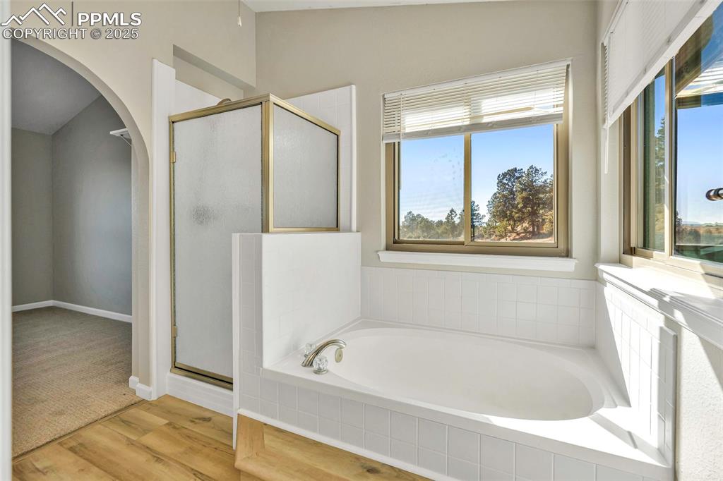 Image 30 of 47: Bathroom with a garden tub, light wood-style floors, a shower stall, and lo
