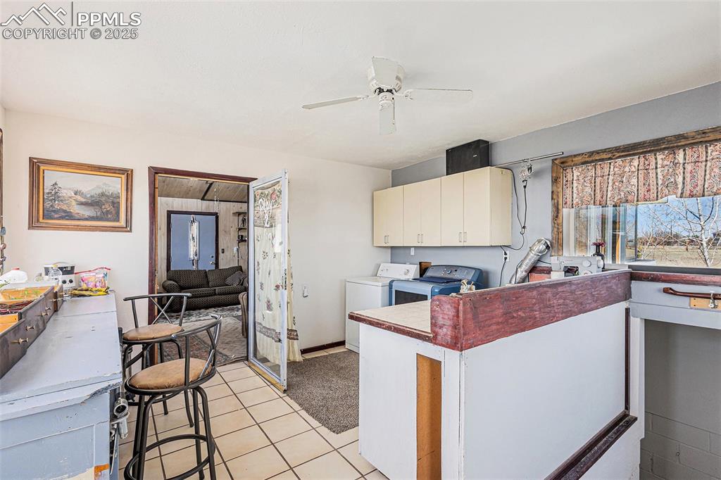Image 14 of 25: Kitchen with white cabinets, ceiling fan, a peninsula, light tile patterned