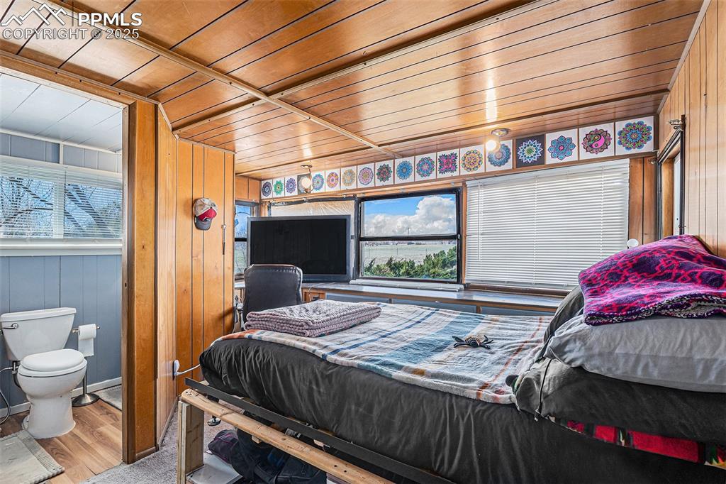 Image 9 of 25: Bedroom with wooden walls, wooden ceiling, and wood finished floors