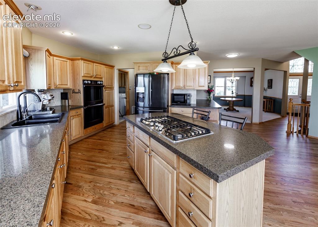 Image 14 of 48: Kitchen featuring wood-finish flooring, light wood cabinetry, stone-finish