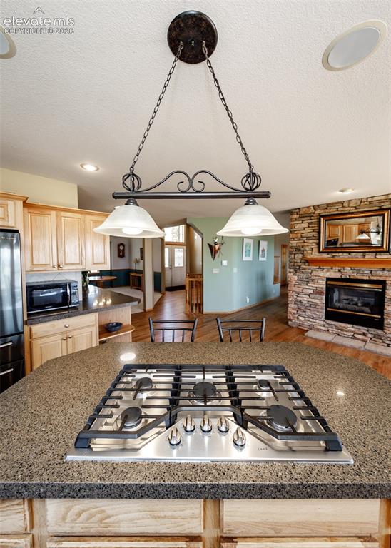 Image 15 of 48: Kitchen island with an integrated stainless steel gas cooktop and granite-s