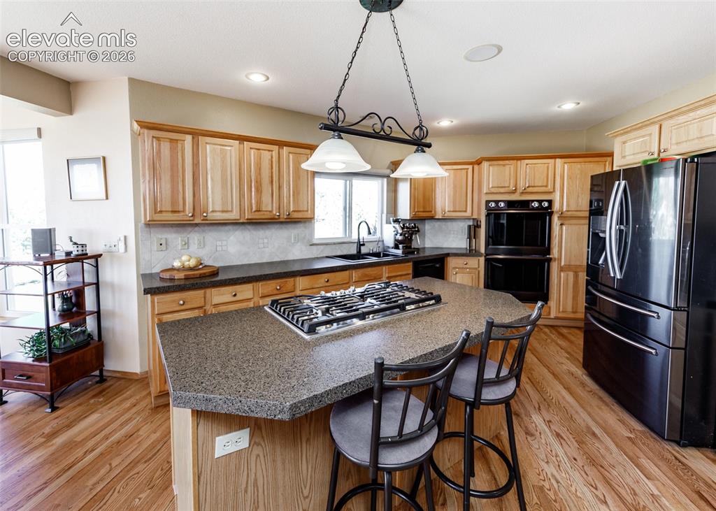 Image 16 of 48: Kitchen featuring wood-finish flooring, natural wood cabinetry, a center is