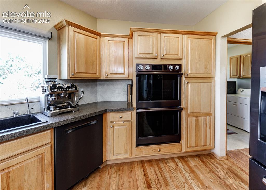 Image 17 of 48: Wood-finish flooring, light wood cabinetry, double wall ovens, integrated d