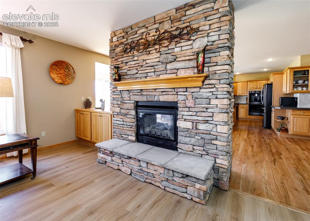 Image 20 of 48: Stone-faced fireplace with a hearth and wood mantel