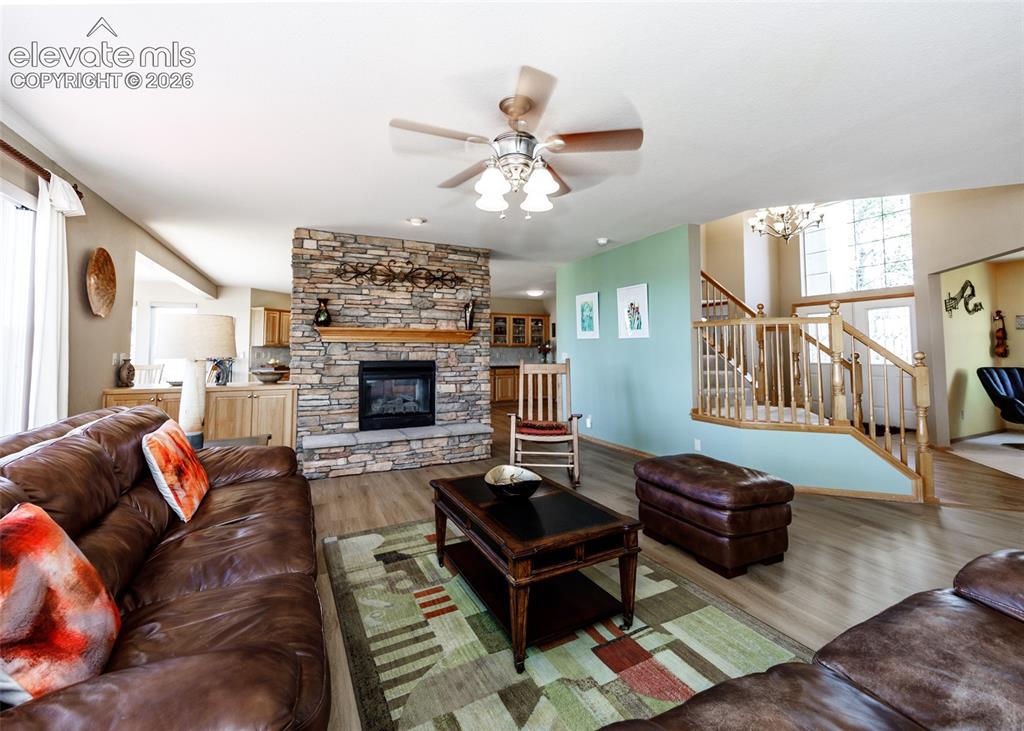 Image 21 of 48: Spacious living area featuring a stone-clad fireplace with a wood mantel, w