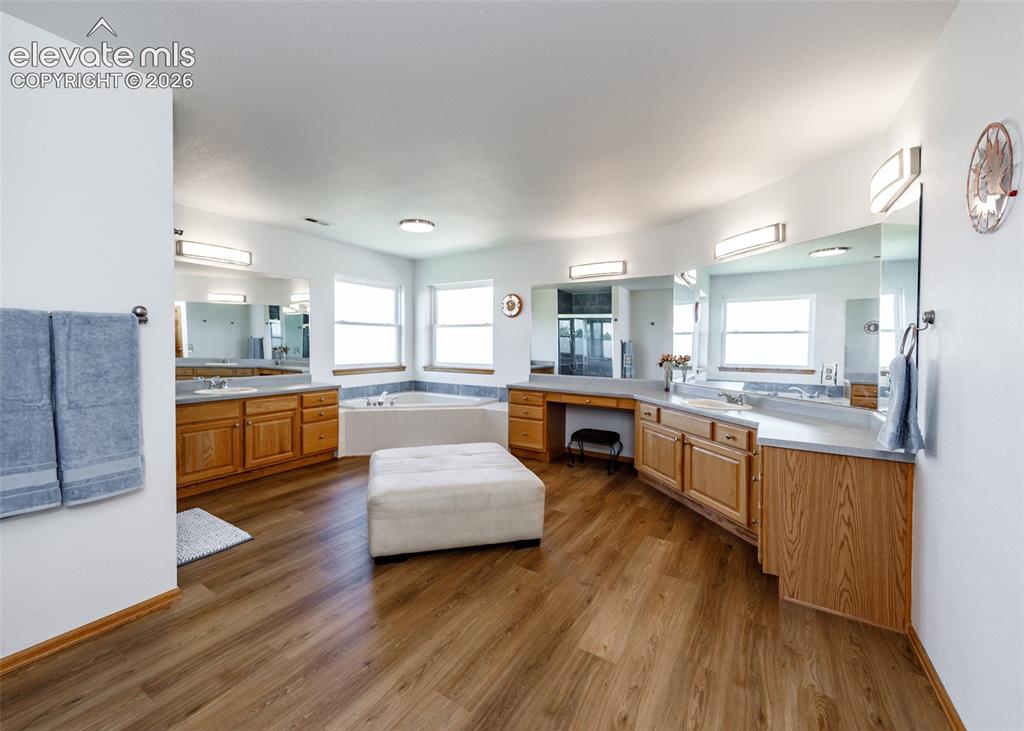 Image 26 of 48: Dual vanity with wood-finish cabinetry and light countertops