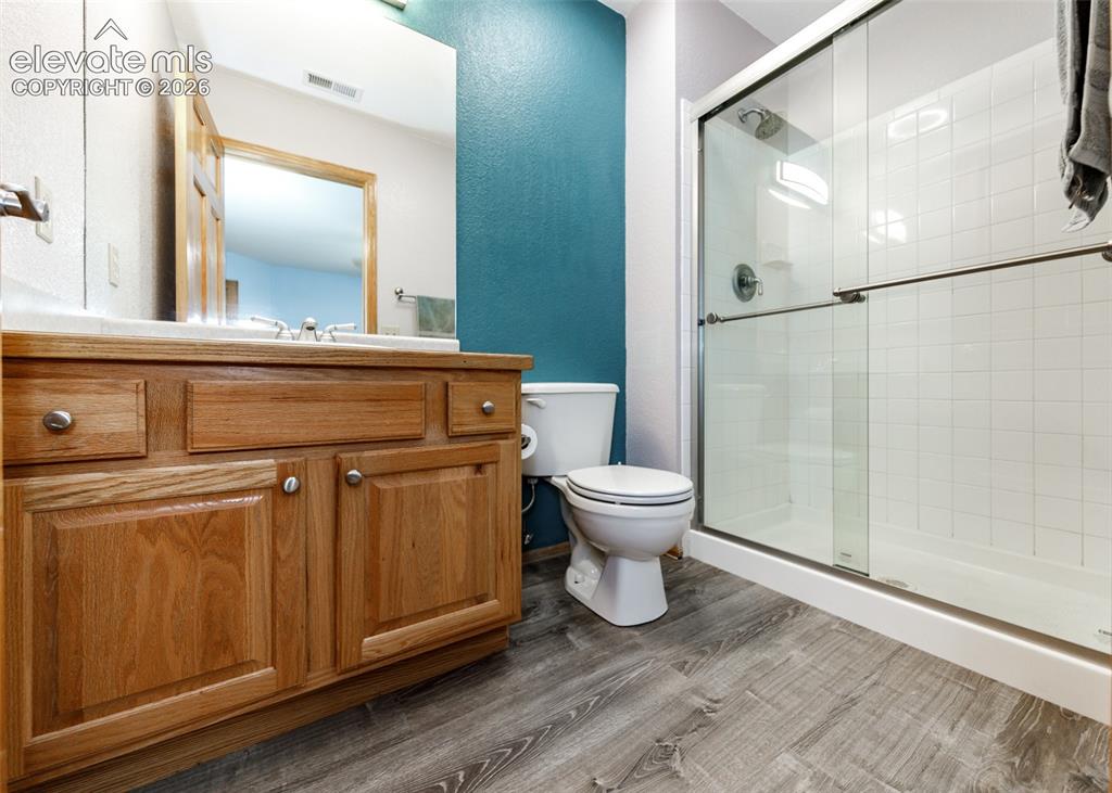 Image 30 of 48: Wood-finish flooring with a vanity featuring natural wood cabinetry and a w