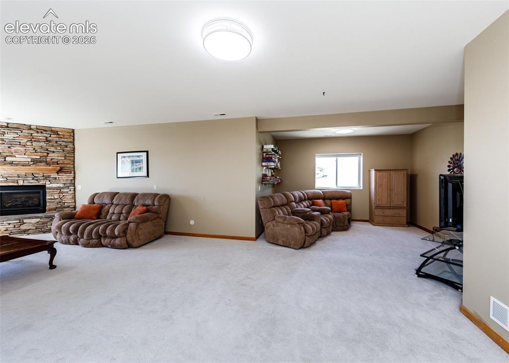 Image 34 of 48: Spacious interior with neutral carpeting, stone-clad fireplace, and integra