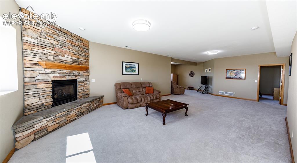 Image 35 of 48: Stone-clad fireplace with a wood mantle, an integrated hearth, and a carpet