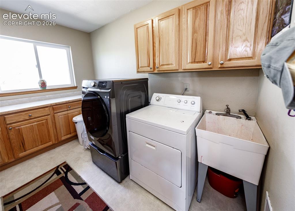 Image 41 of 48: Laundry area featuring wood-finish cabinetry, light-toned countertops, and 