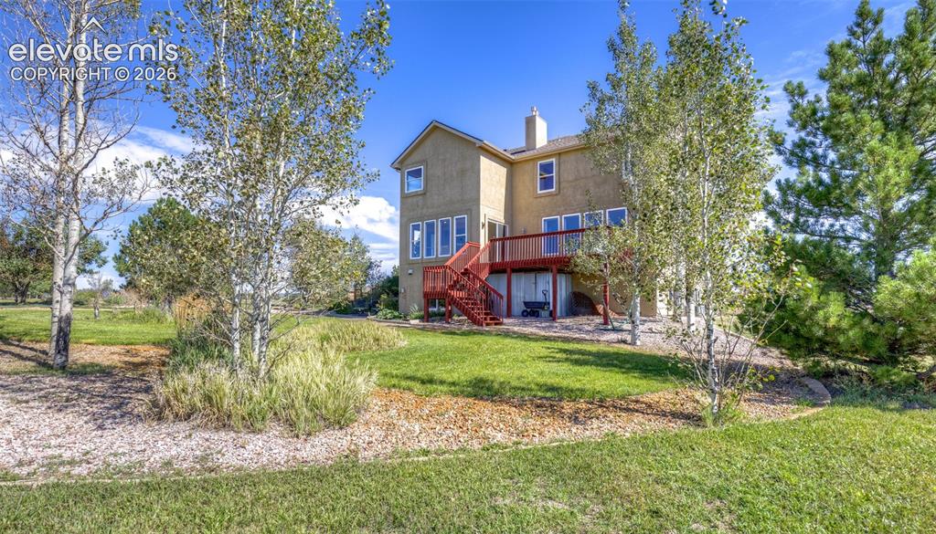 Image 46 of 48: Stucco exterior with a multi-level red-stained wood deck, featuring multipl