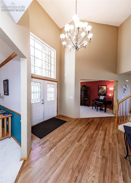 Image 7 of 48: Foyer featuring wood-finish flooring, a vaulted ceiling, a decorative chand