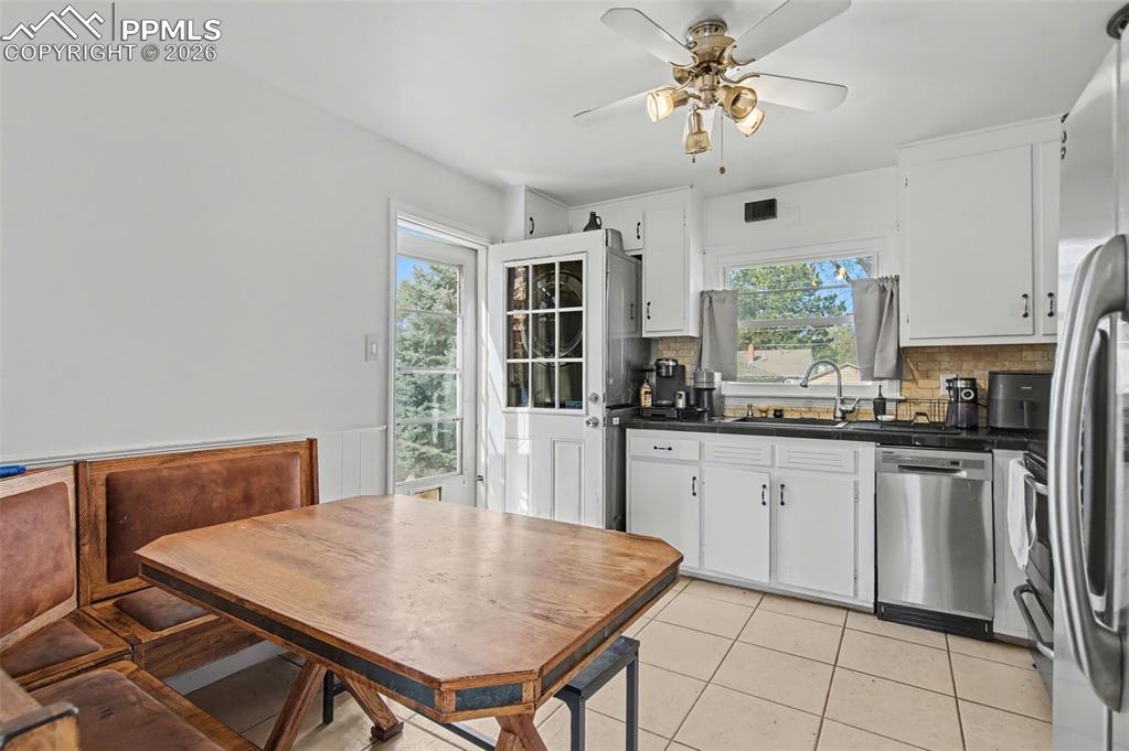 Image 10 of 28: Kitchen with a ceiling fan, stainless steel appliances, dark countertops, w