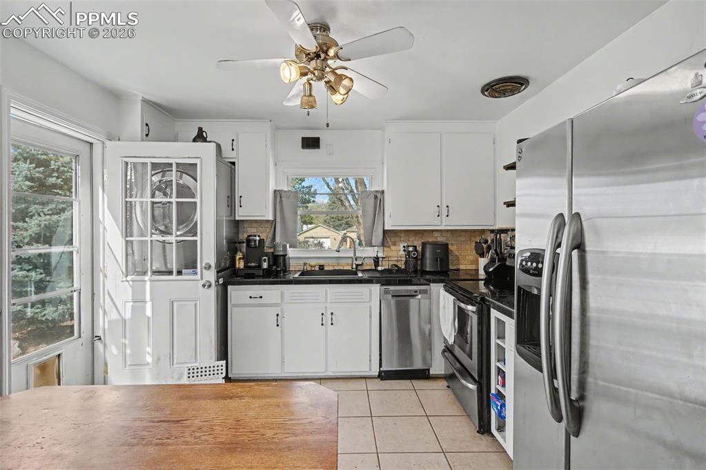 Image 11 of 28: Kitchen with stainless steel appliances, white cabinets, ceiling fan, light
