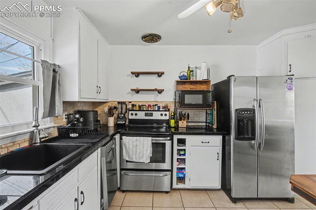 Image 12 of 28: Kitchen with stainless steel appliances, white cabinets, and light tile pat