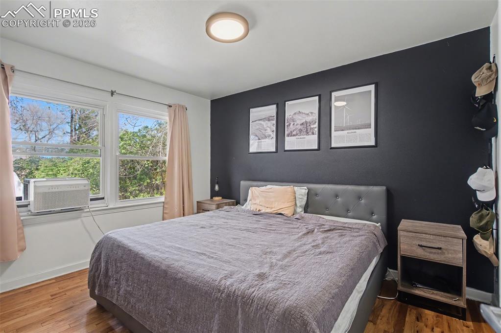 Image 15 of 28: Bedroom with wood finished floors and an accent wall