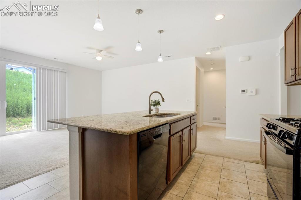 Image 11 of 36: Kitchen with light carpet, black dishwasher, gas range oven, hanging light 