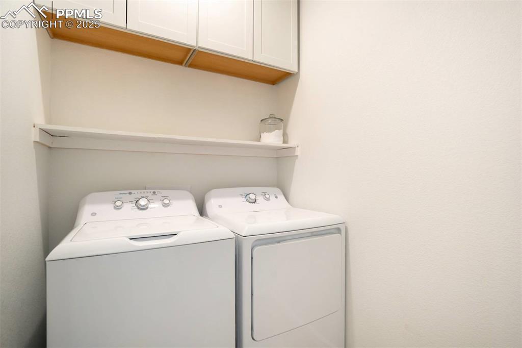 Image 14 of 36: Laundry area featuring cabinet space and washer and clothes dryer
