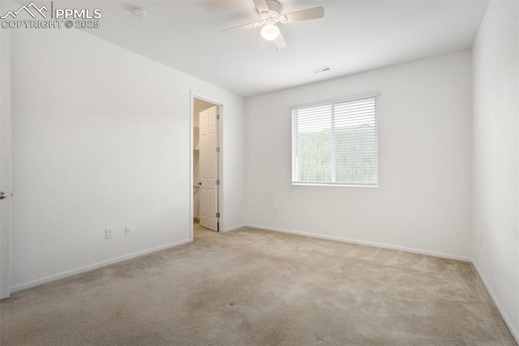 Image 16 of 36: Spare room featuring light carpet, ceiling fan, and a smoke detector