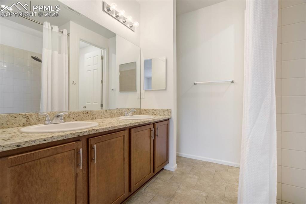 Image 19 of 36: Full bathroom featuring double vanity and curtained shower