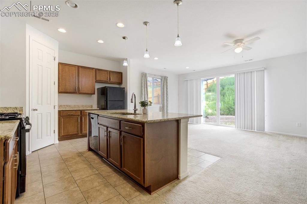 Image 2 of 36: Kitchen with black appliances, a ceiling fan, recessed lighting, light ston