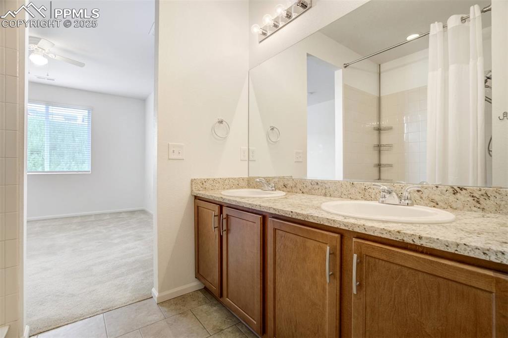 Image 21 of 36: Full bathroom featuring double vanity, tile patterned floors, curtained sho